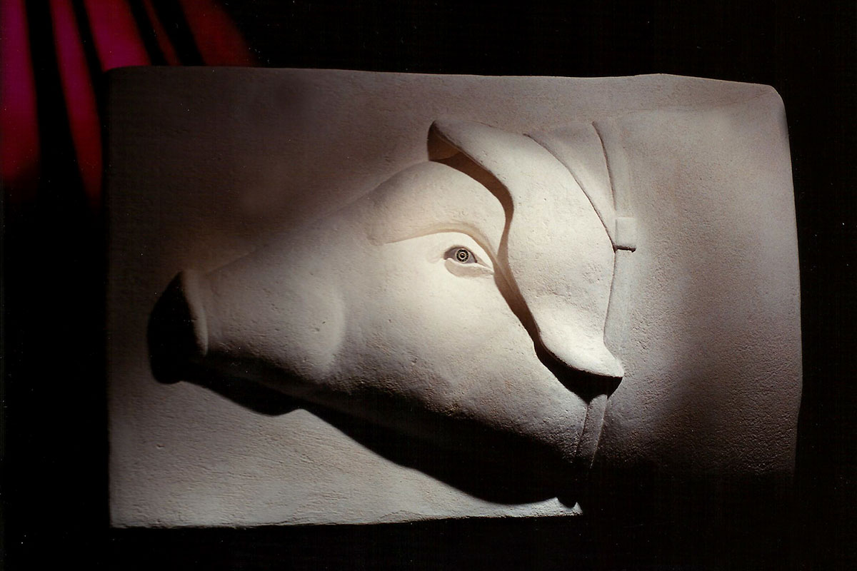 Rilievo in stucco bianco con una testa di maiale di profilo
